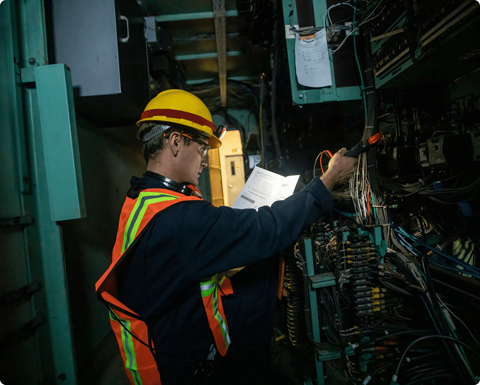 Engineer examining wiring in dimly lit area.