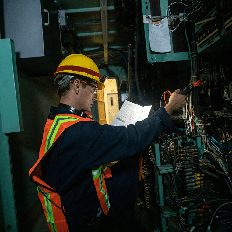 Engineer examining wiring in dimly lit area.